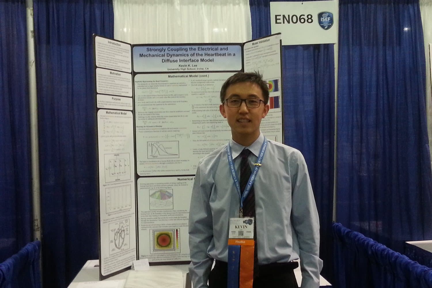 Kevin standing beside his ISEF board on a computational model of the heartbeat.